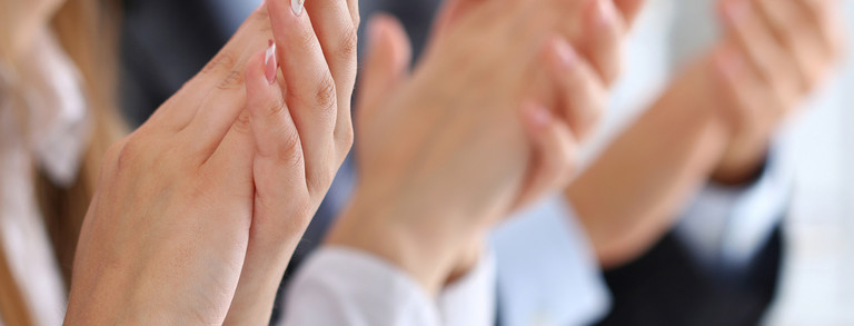 Several hands of women and men clap.